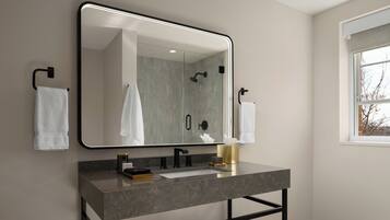 Une salle de bain moderne avec un grand miroir, un lavabo et une douche.