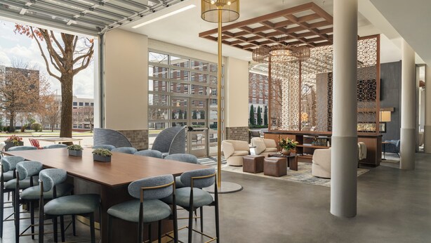 A spacious indoor area with a long table, multiple chairs, and a seating area with sofas and a TV.