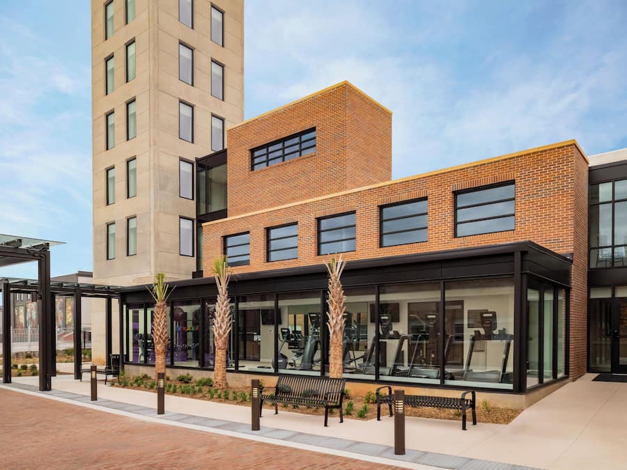 A modern building with a brick facade, large windows, and outdoor exercise equipment.