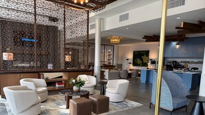 A spacious lobby with modern furniture, a decorative partition, and a visible kitchen area.
