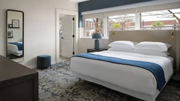 A bedroom with a bed, a nightstand, a mirror, a window, and a door.