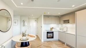 A modern kitchen with a central island, white cabinetry, and a herringbone wood floor. - 1 Bed Flat - Sleeps 2 - Parking - Wifi (Dorchester)