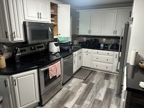 A kitchen with white cabinets, stainless steel appliances, and a patterned floor. - Holly Acres Retreat (Mount Holly)