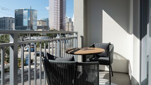 Un balcón con mesa y sillas, con vista a un paisaje urbano de edificios altos.