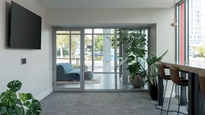 Una habitación moderna con un televisor grande, puertas de vidrio correderas a un balcón y un comedor con sillas y mesa.