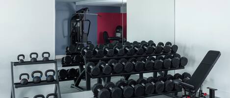 A gym with a bench, kettlebells, and dumbbells.