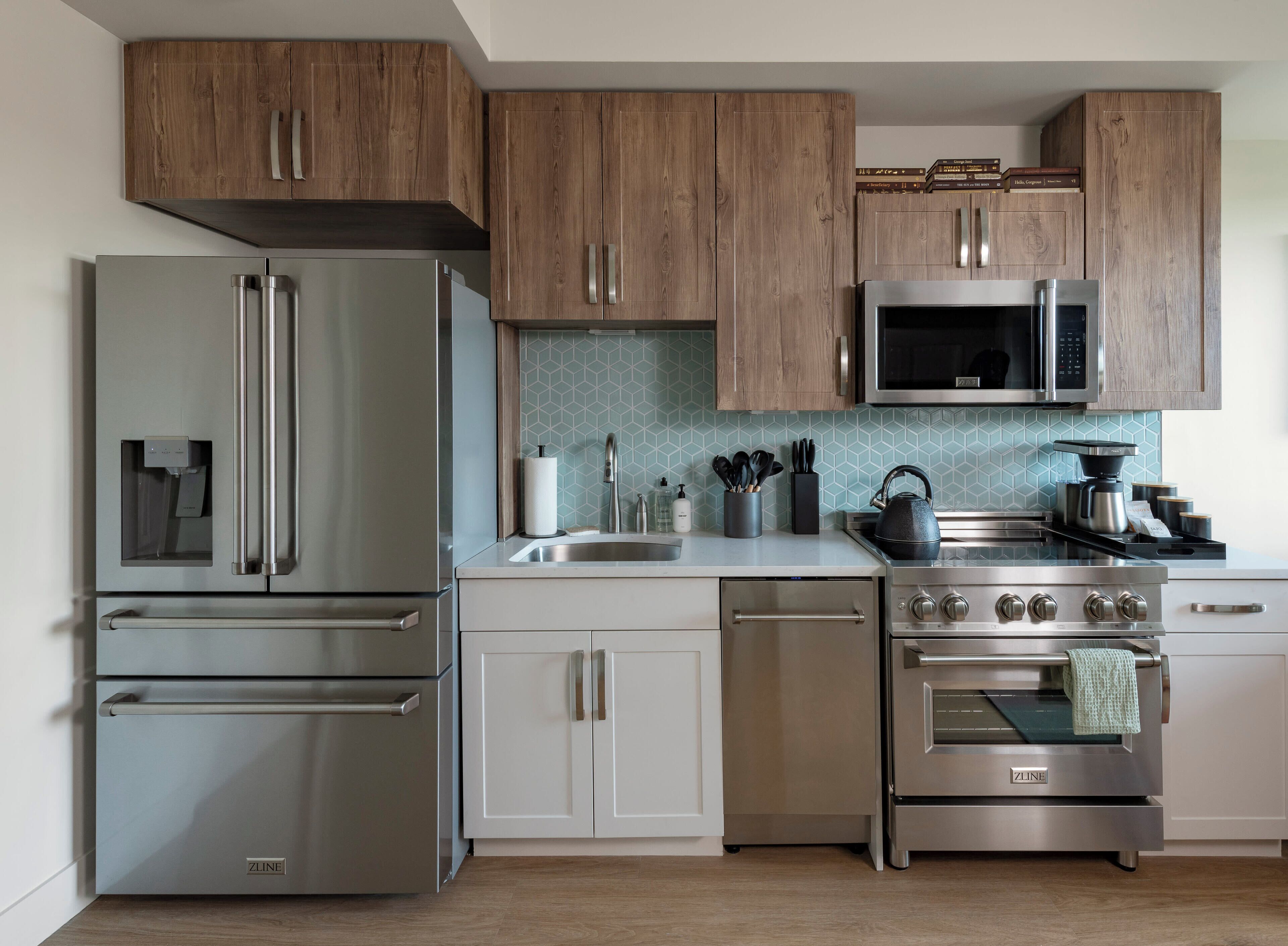 A modern kitchen with stainless steel appliances, wooden cabinets, and a tiled backsplash.