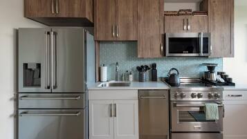 A modern kitchen with stainless steel appliances, wooden cabinets, and a tiled backsplash.