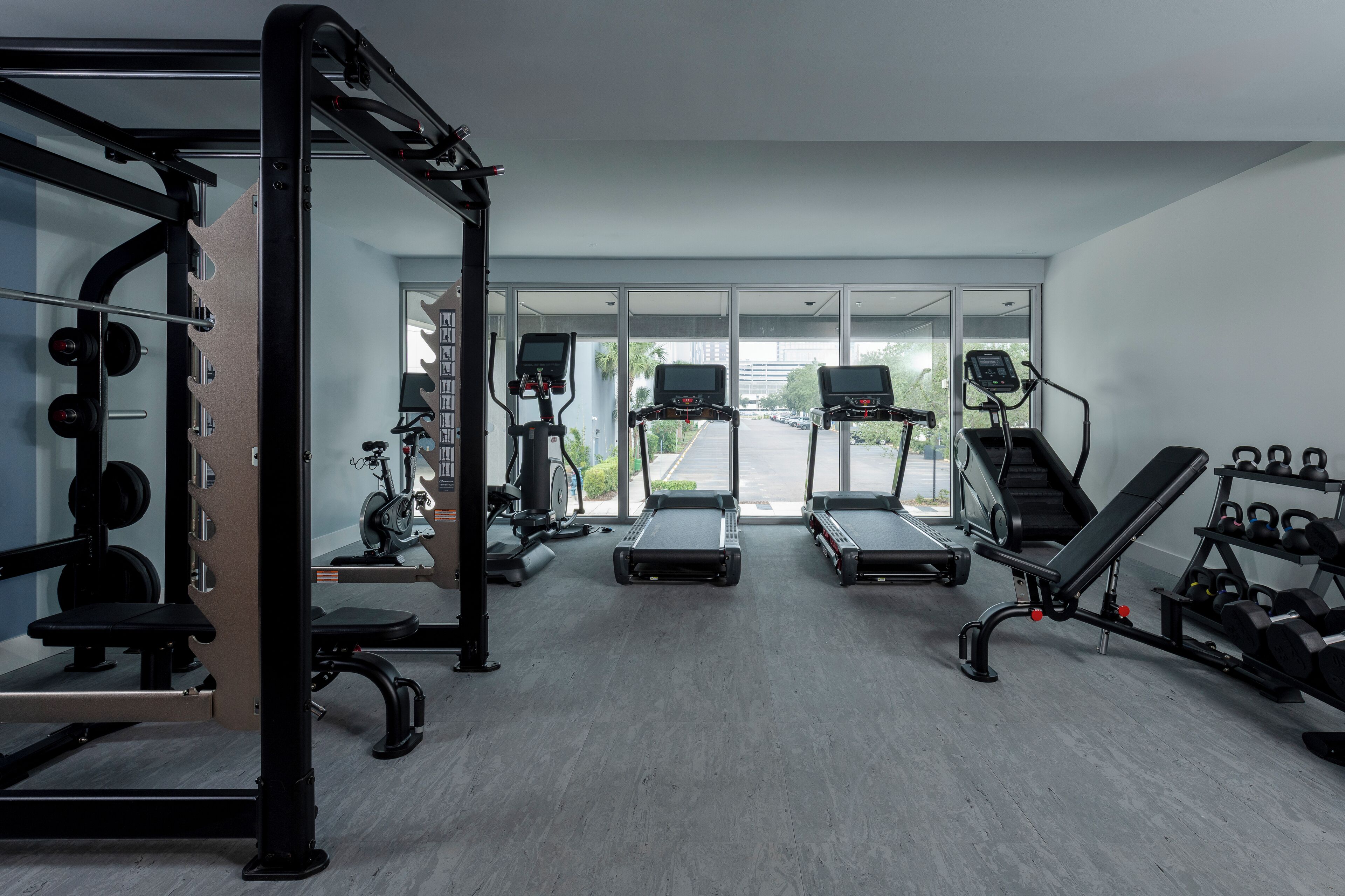 Een moderne sportschool met loopbanden, een rek voor squats en losse gewichten.