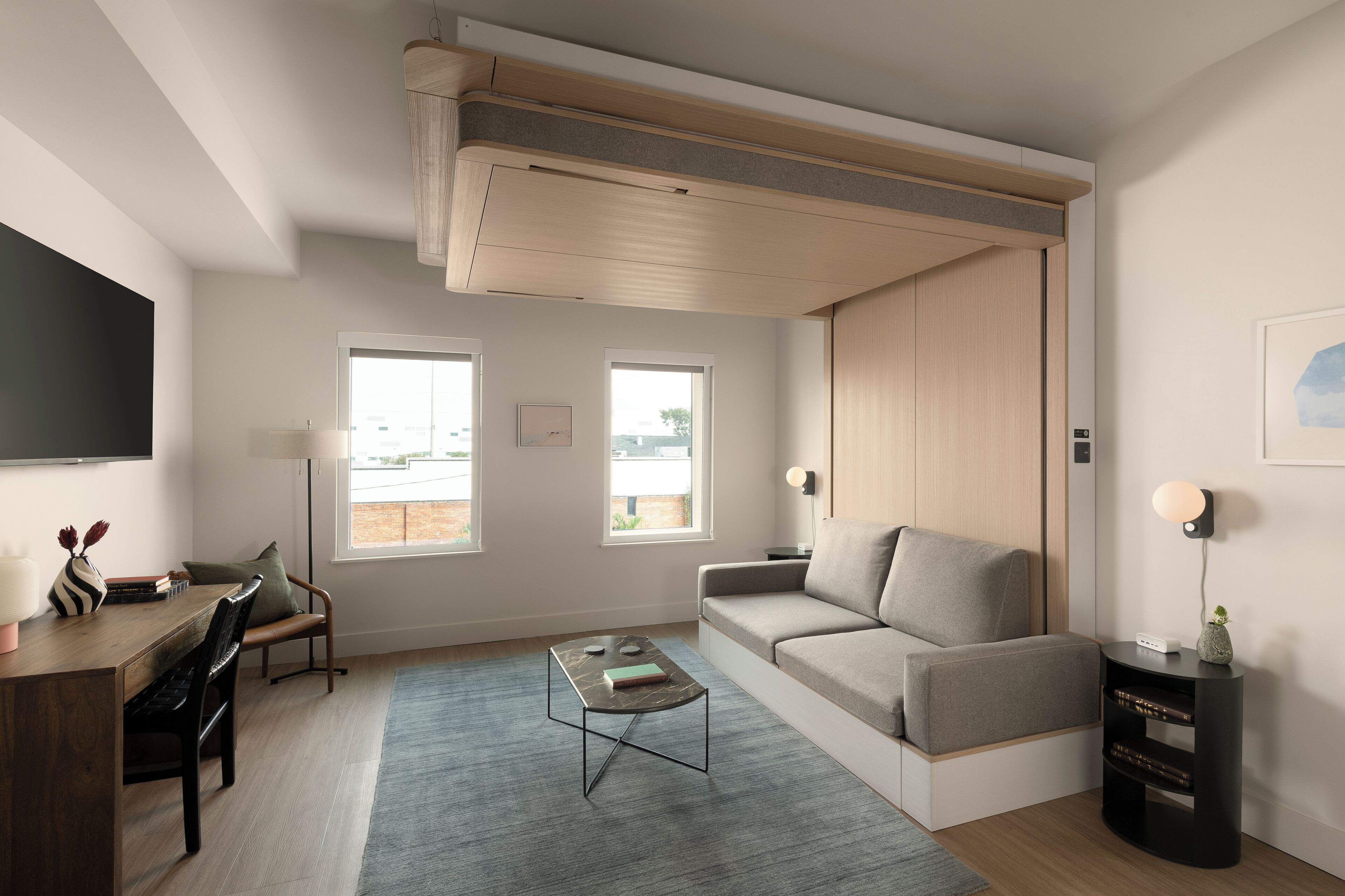 A modern living room with a sofa, coffee table, and a flat-screen TV mounted on the wall.