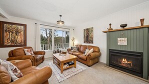 A cozy living room with leather sofas, a fireplace, and artwork on the walls.