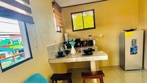Una cocina compacta con comedor, una silla azul y un refrigerador.