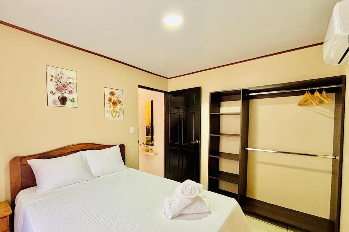 Une chambre d’hôtel comprenant un lit, une armoire et une porte donnant sur une autre pièce.