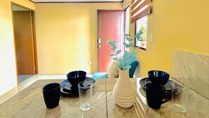 Un comedor con una mesa de mármol, cuencos negros y vasos transparentes.
