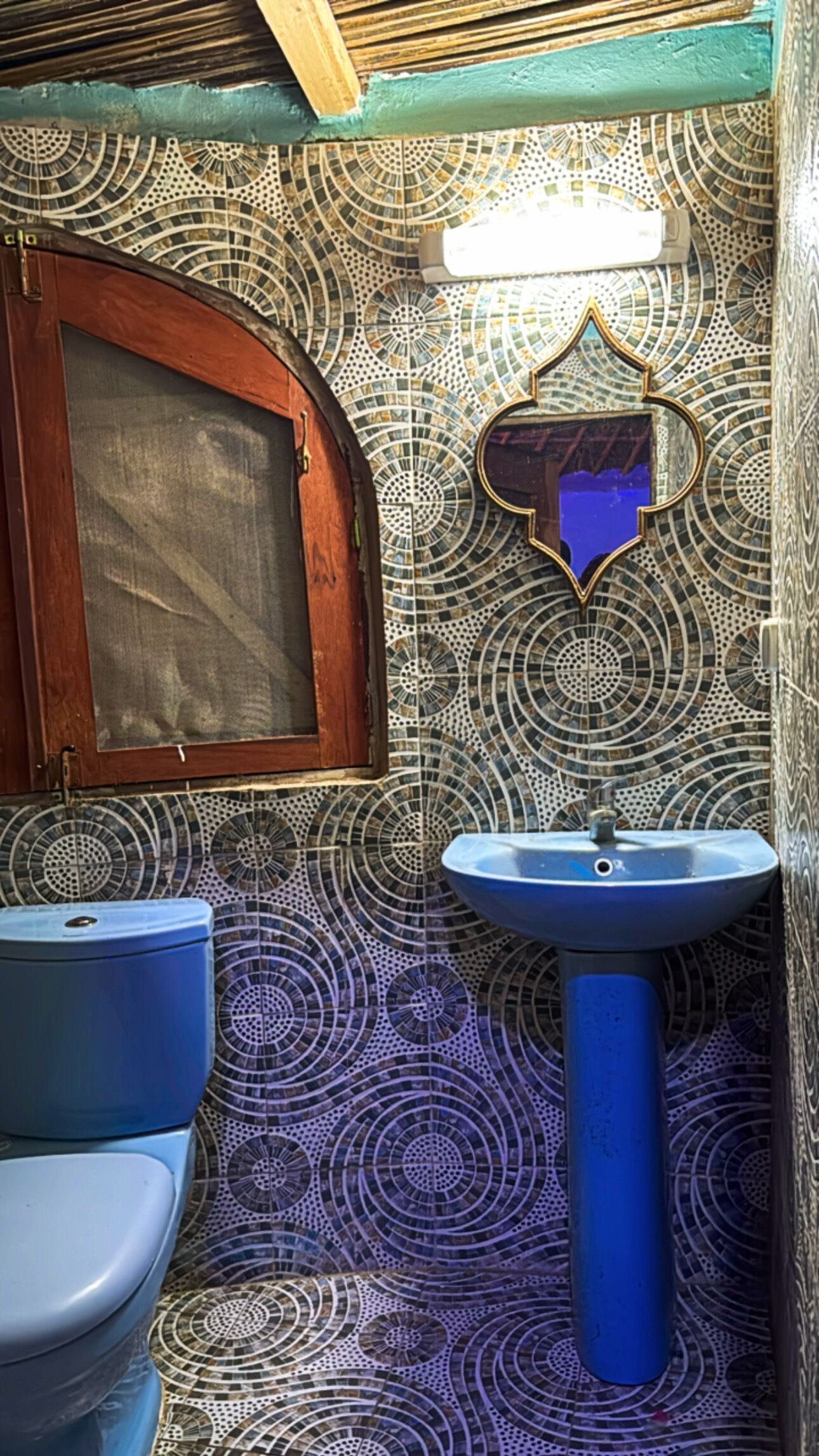 Ein Badezimmer mit einer blauen Toilette, einem blauen Waschbecken und einem Spiegel mit herzförmigem Rahmen.