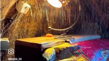 A cozy attic bedroom with a rustic aesthetic, featuring a unique lamp, a small table, and colorful bedding.