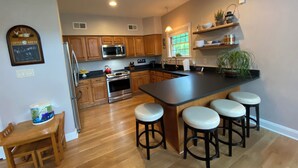 A modern kitchen with wooden cabinets, a stainless steel stove, and a large island with bar stools.
