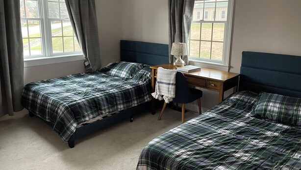 A room with two beds, a desk, and a chair.