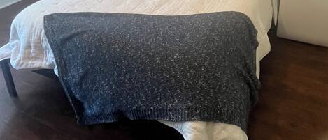 Une chambre avec un grand lit, une table de chevet, une fenêtre avec des stores et un thermostat fixé au mur.