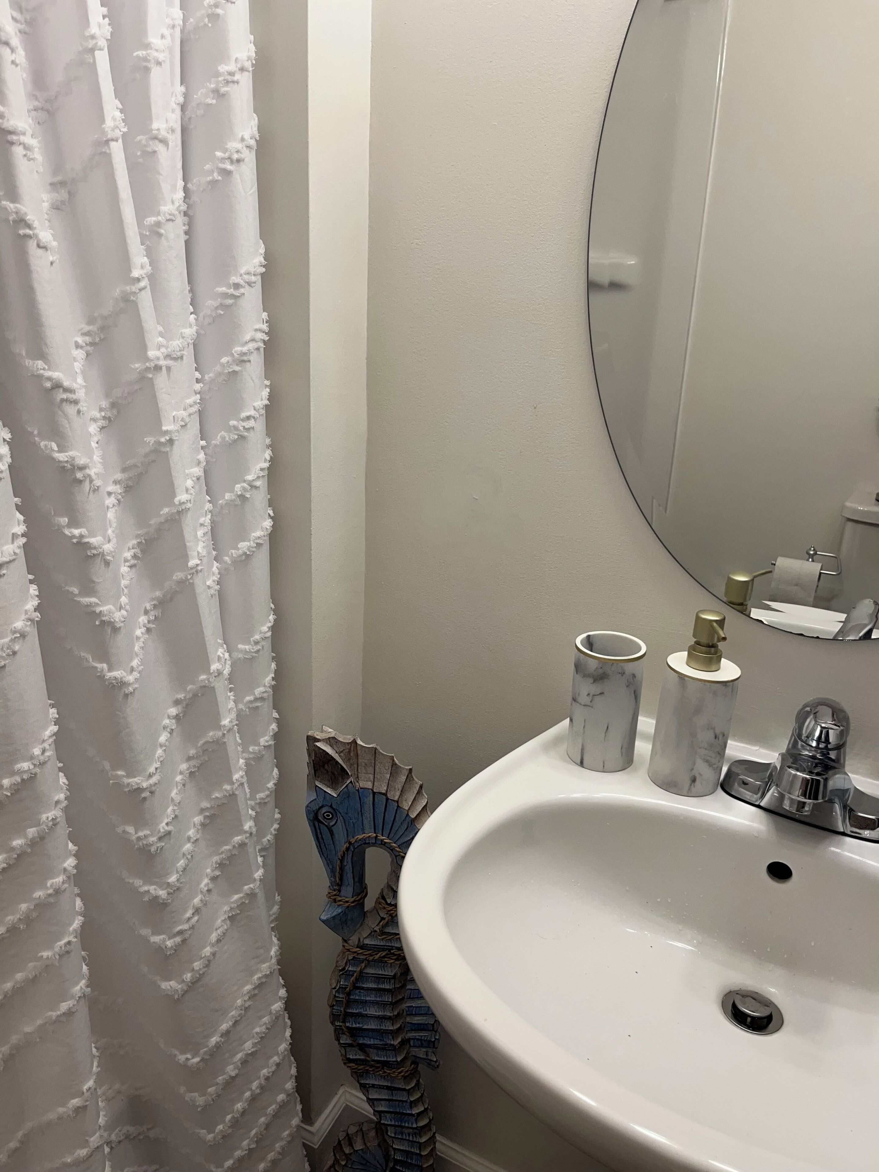 A bathroom with a white sink, a mirror, and a shower curtain.