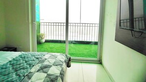 A bedroom with a bed, a window, and a TV on the wall. - Charming Apartment with best Balcony & view in Zirakpur (Zirakpur)
