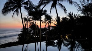 A pool reflecting palm trees and a sunset over the ocean. - Artist Cliffside Home with private beach access and cabana and two cats. (Punta de mita Bahía de banderas)