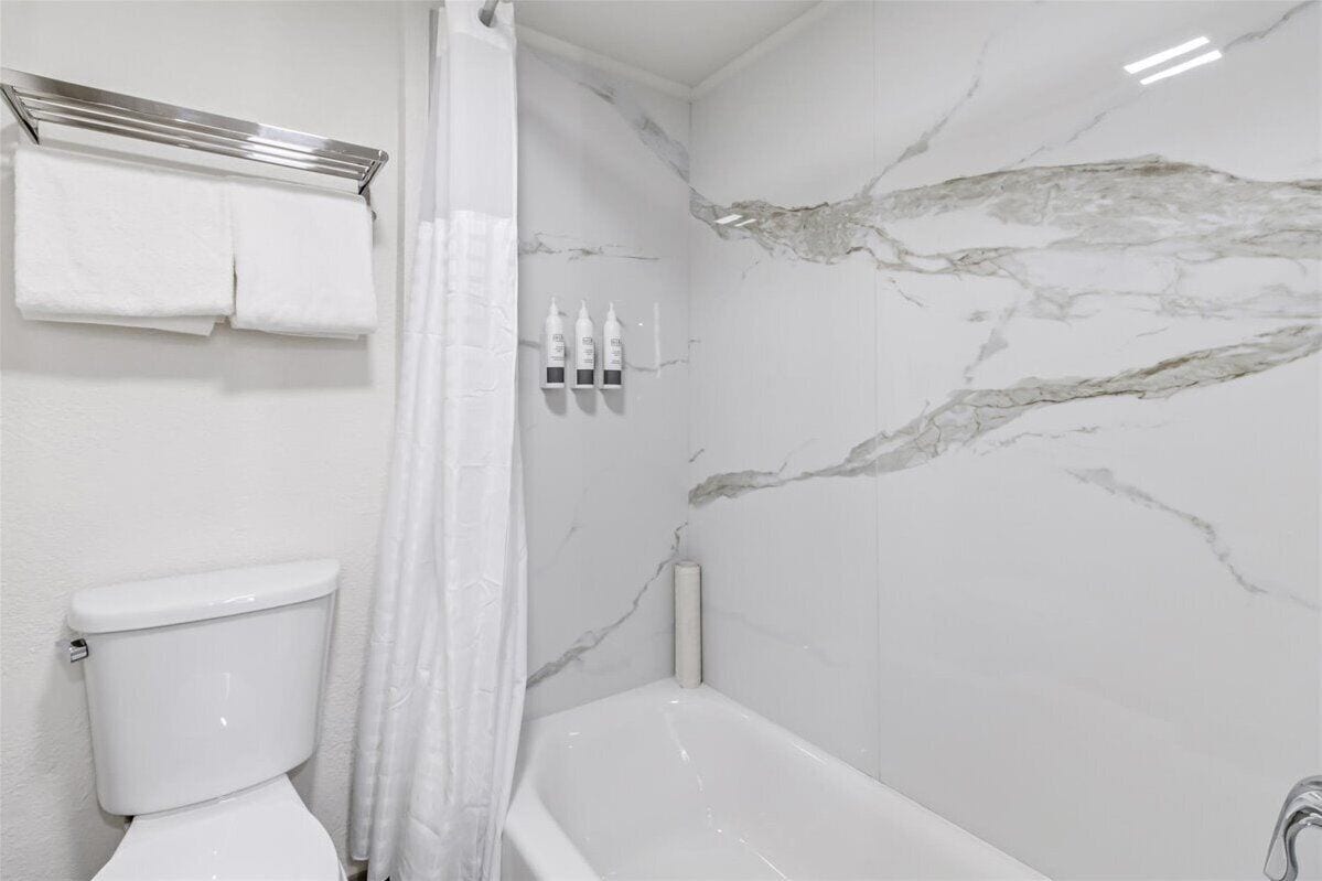 Un baño con inodoro, bañera y cortina de ducha.