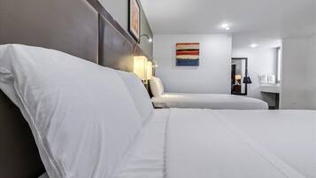 Une chambre d’hôtel avec deux lits, une table de chevet, une lampe et un tableau au mur.