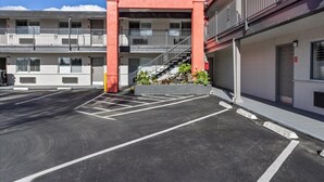 Monikerroksinen rakennus, jossa on punainen sisäänkäynti, parkkipaikka ja portaikko, joka johtaa parvekkeelle.