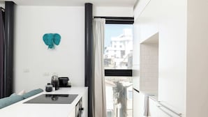 A modern kitchen with a central island, a view through a glass door, and a teal heart decoration on the wall.
