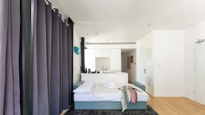 A modern bedroom with a bed, a black rug, and a bathroom visible in the background.