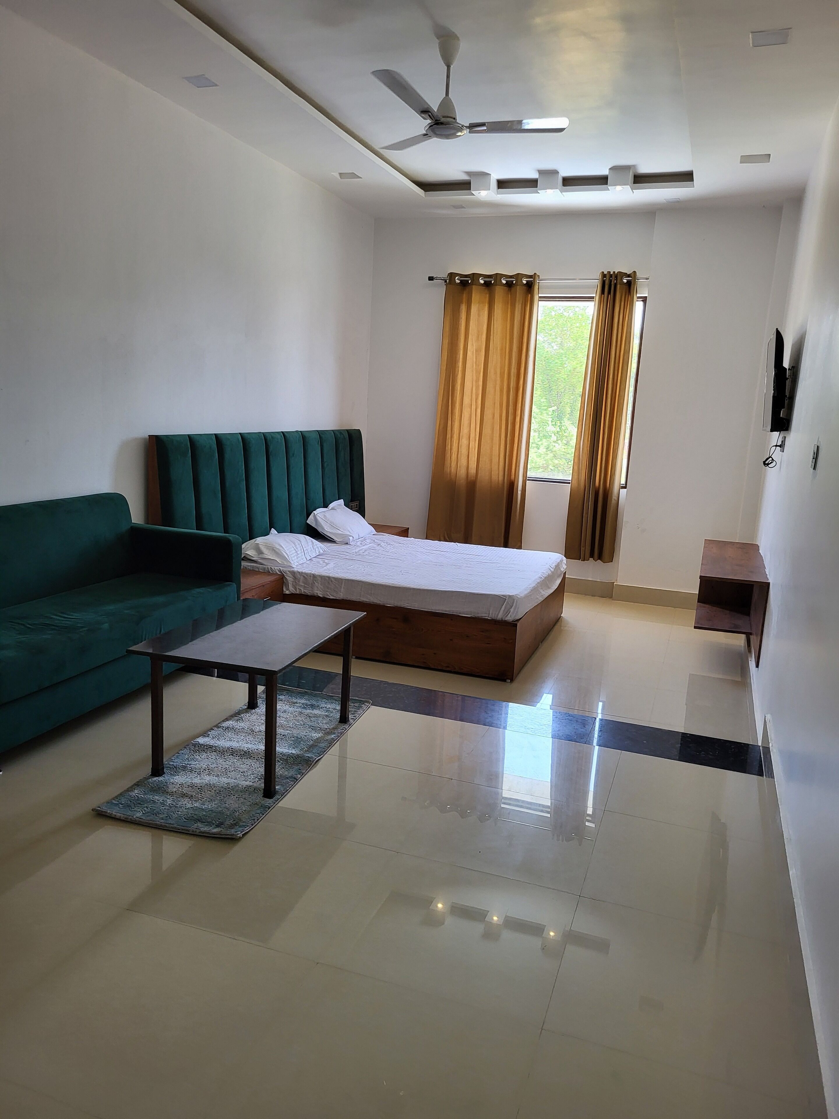A modern hotel room with a bed, green sofa, and a small table.