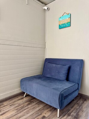 A corner room with a blue sofa, a wooden floor, and a wall with a beach-themed decoration. - Tikaban Kreol (Pointe d'Esny)