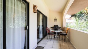 A balcony with a table and chairs, a sliding glass door, and a view of a building and foliage. - D-302 2 bedroom Penthouse Condo (Cabo San Lucas)
