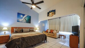 A hotel room with a bed, a sofa, a television, and a ceiling fan. - D-302 2 bedroom Penthouse Condo (Cabo San Lucas)