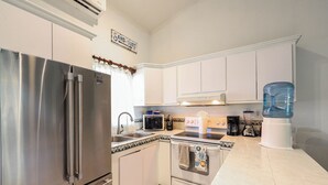 A modern kitchen with stainless steel appliances, white cabinetry, and a water dispenser. - D-302 2 bedroom Penthouse Condo (Cabo San Lucas)