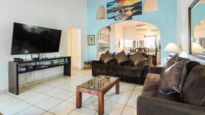 A living room with a flat-screen TV, a glass coffee table, and a brown leather sofa. - D-302 2 bedroom Penthouse Condo (Cabo San Lucas)