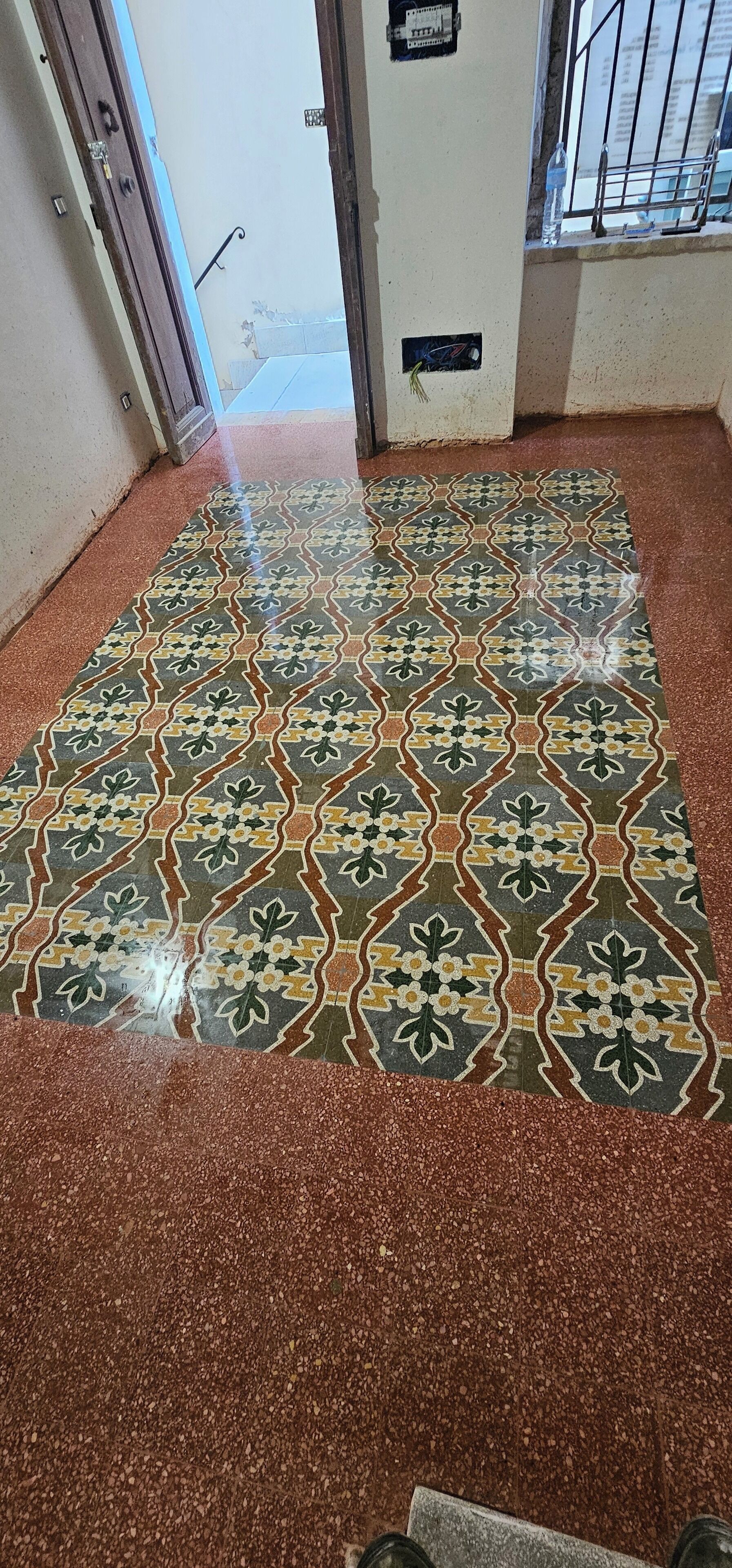 Ein Korridor mit einem gemusterten Boden und einer Tür zu einem anderen Raum.