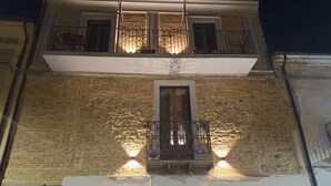 Edifici amb façana de pedra, un balcó amb barana de ferro forjat i una finestra amb porta.