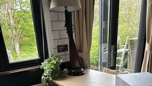 A kitchen with a stove, cabinets, a window with curtains, and a plant.