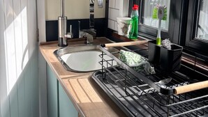 A kitchen with a sink, faucet, and a window with a view of greenery.