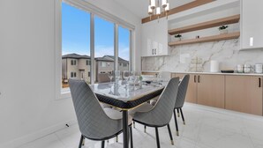 A modern kitchen with a marble countertop, a dining table with chairs, and a view of neighboring houses. - 4 Bedrooms, 3 washrooms, and 2 living rooms, Luxury Home Close to Amenities (Leduc)