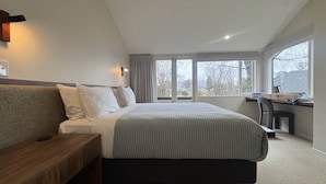 Un dormitorio moderno con una cama grande, un banco de madera, un escritorio y una silla.