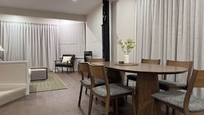 Una sala de estar moderna con comedor, que incluye una mesa redonda de madera, sillas a juego, un sofá y una mesa de centro.