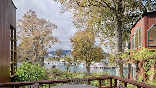 Una terraza de madera con una mesa redonda y sillas, con vista a una masa de agua con barcos y edificios a la distancia.
