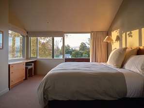 A bedroom with a large bed, a desk, and a window with curtains. - Chalet 6 @ The Retreat (Taupo)