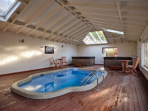 An indoor swimming pool with a wooden deck, a hot tub, and seating areas. - Chalet 8 @ The Retreat (Taupo)