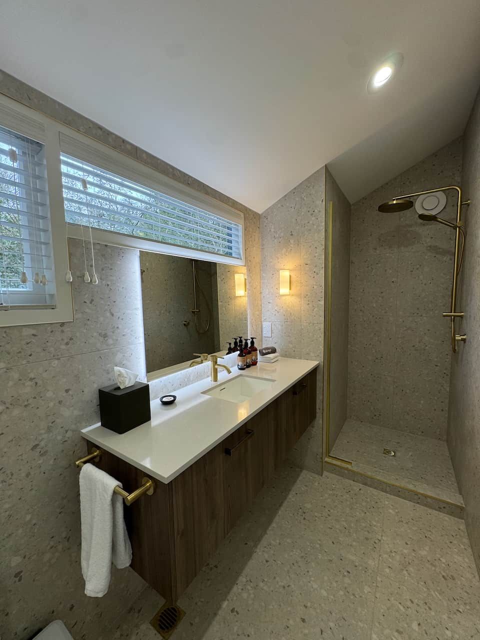 Ein modernes Badezimmer mit einem Doppelwaschtisch, einem großen Spiegel und einer begehbaren Dusche.