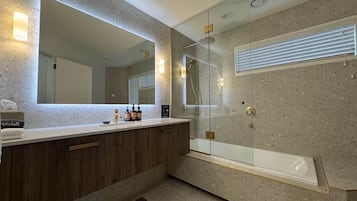 Une salle de bain moderne avec un grand miroir, une baignoire et un espace douche.