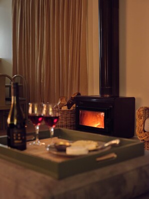 A cozy room with a fireplace, a bottle of wine, and glasses on a tray.
